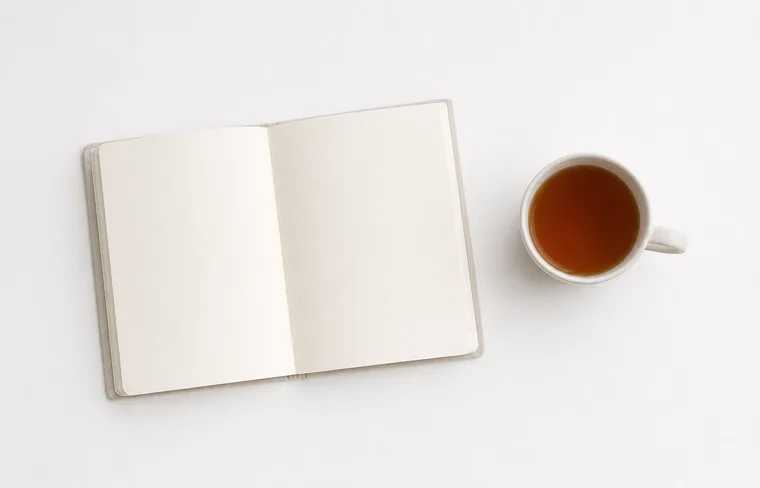 Open notebook and a cup of tea on a white table